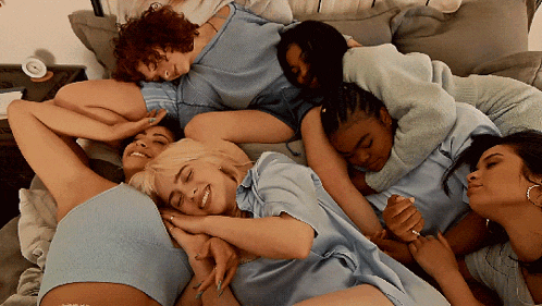 a group of women are laying on a bed hugging and smiling