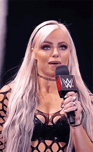 a woman with long blonde hair is holding a microphone with a w on it .