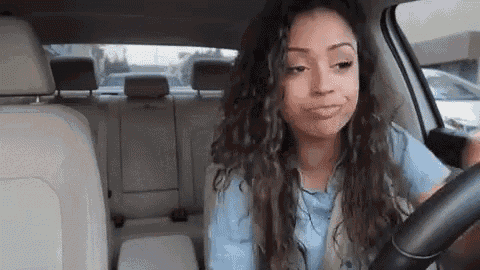 a woman is sitting in the driver 's seat of a car and smiling .