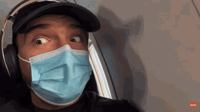 a man wearing a face mask and headphones is looking at the camera