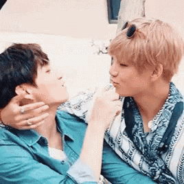 two men are sitting next to each other on a couch and kissing each other .