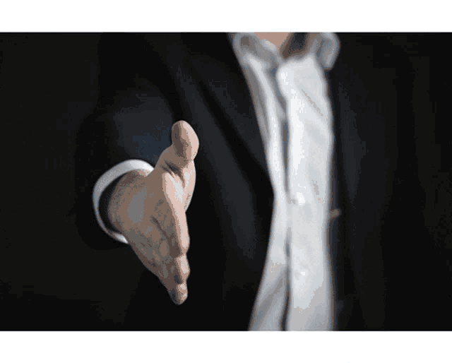 a man in a suit is reaching out his hand to shake