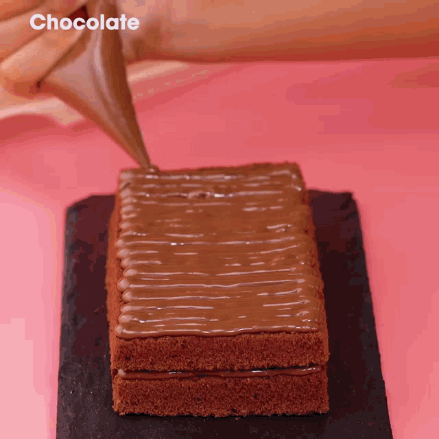 a piece of chocolate cake is being decorated with chocolate icing