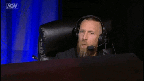 a man wearing a headset is sitting in front of a screen that says all elite wrestling