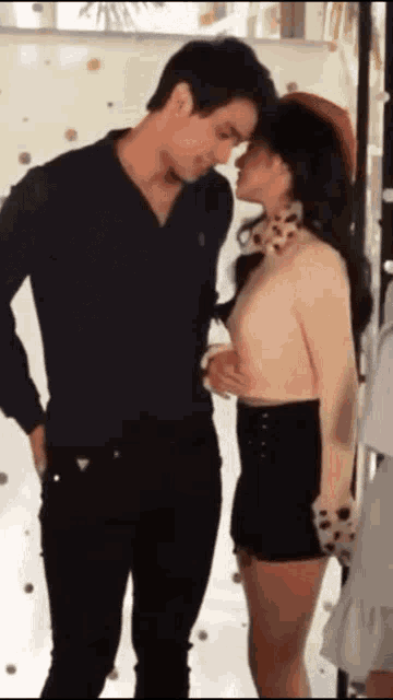 a man and a woman are standing next to each other and the woman is kissing the man on the forehead