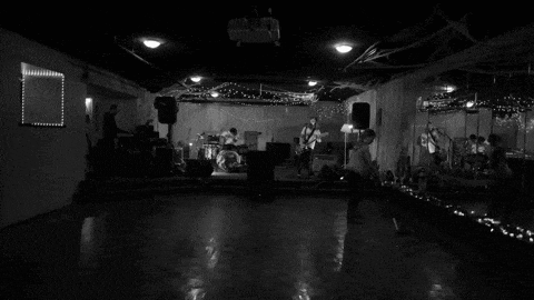 a black and white photo of a band playing instruments in a dark room