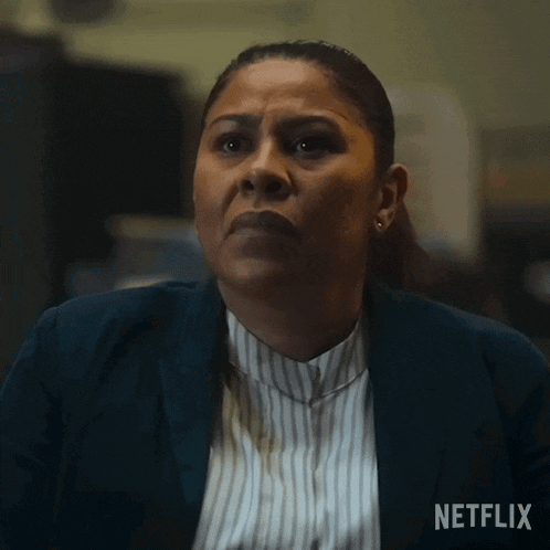 a woman in a striped shirt and a blue jacket is sitting in front of a netflix logo