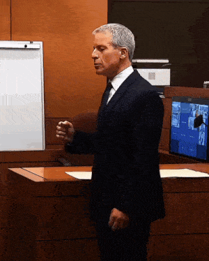 a man in a suit and tie stands at a podium in front of a screen that says ' epson '