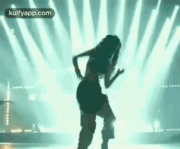 a woman is dancing on a stage in front of a crowd of people .