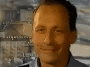 a close up of a man 's face with a blurry background behind him .