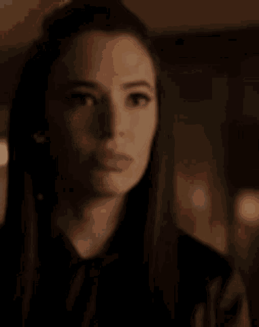 a close up of a woman 's face in a dark room with a serious look on her face .