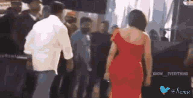 a woman in a red dress is walking in front of a crowd with a blue bird that says hemu