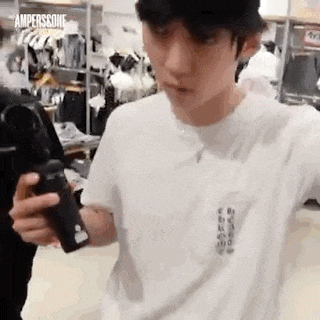 a man in a white shirt is holding a camera in a store .