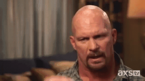 a bald man with a beard is making a funny face while sitting on a couch .
