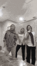 three women are standing next to each other in a room and dancing .