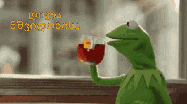 kermit the frog is drinking a cup of lipton tea in front of a window
