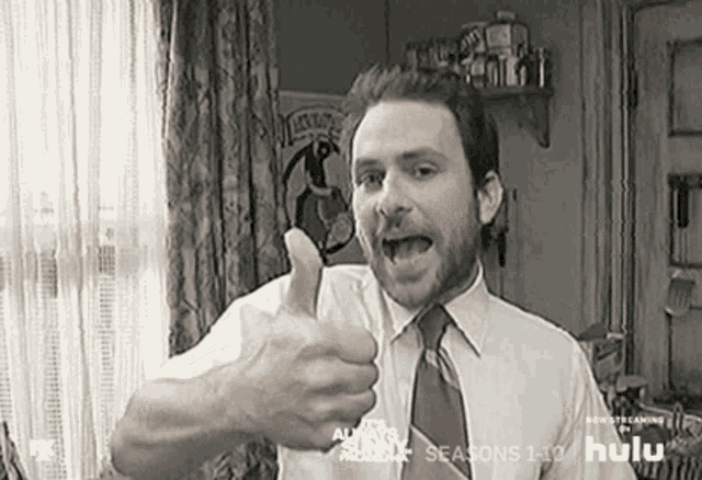 a man in a white shirt and tie is giving a thumbs up sign .