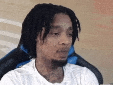 a man with dreadlocks and a beard is sitting in a blue chair .