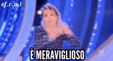 a woman in a polka dot dress is dancing on a stage with the words e meraviglioso written on the bottom .