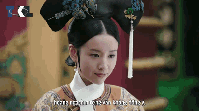a woman in a traditional costume with foreign writing on the bottom of the screen