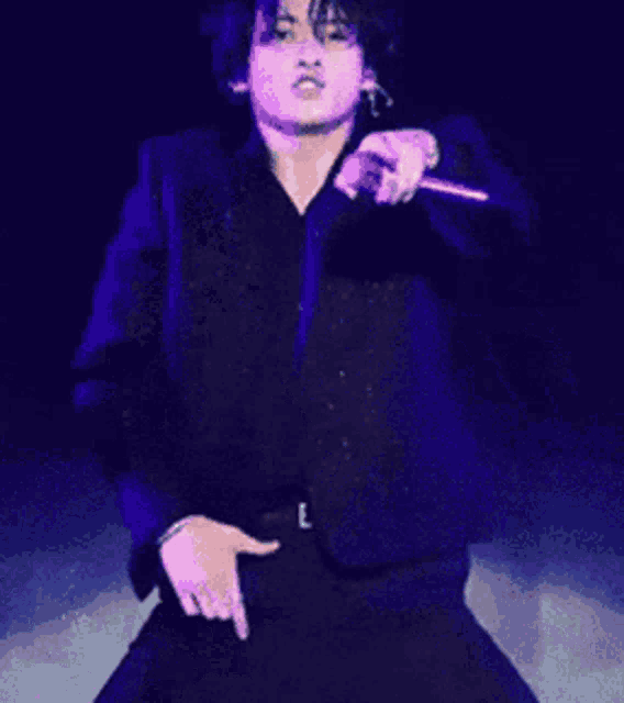 a man wearing sunglasses and a black shirt is singing into a microphone on stage .