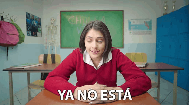 a girl in a red sweater sits at a desk in front of a chalkboard that says chulsa