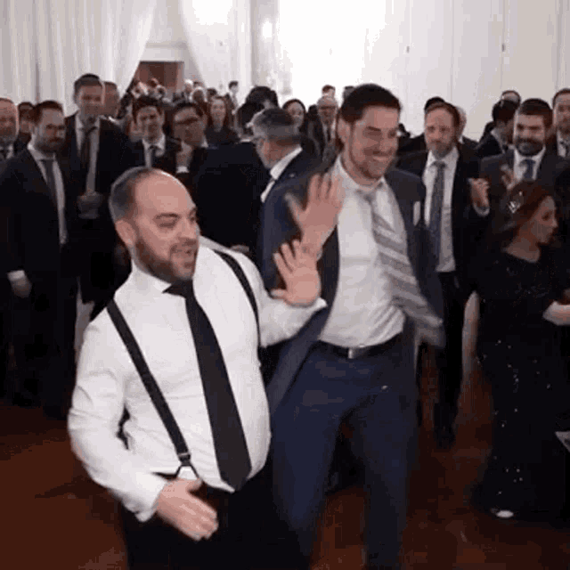a man in a suit and tie is dancing with another man in a white shirt and suspenders .