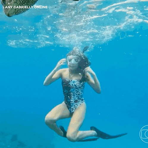 a woman in a swimsuit is swimming next to a sea turtle and the words any gabrielly online are above her