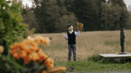 a little boy is standing in a field holding a book