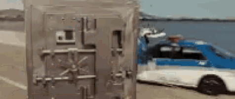 a blue and white police car is towing a safe on the beach .
