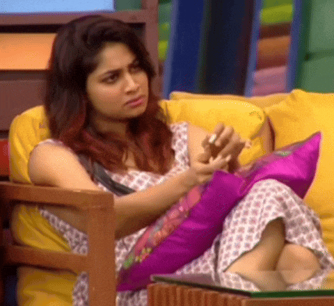 a woman is sitting on a couch with a pink pillow and a yellow pillow .