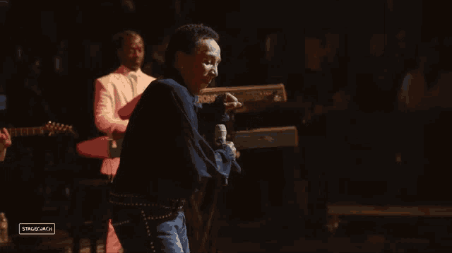 a man singing into a microphone with the word stage on the bottom