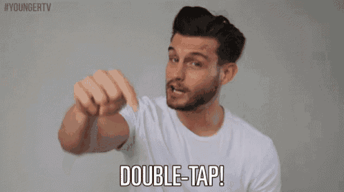 a man in a white shirt is pointing at the camera and saying double tap