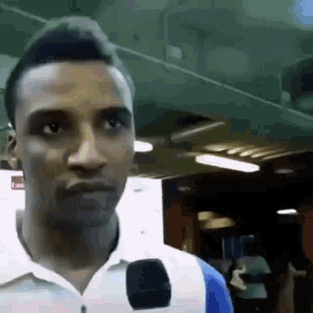 a man is talking into a microphone while wearing a white shirt .