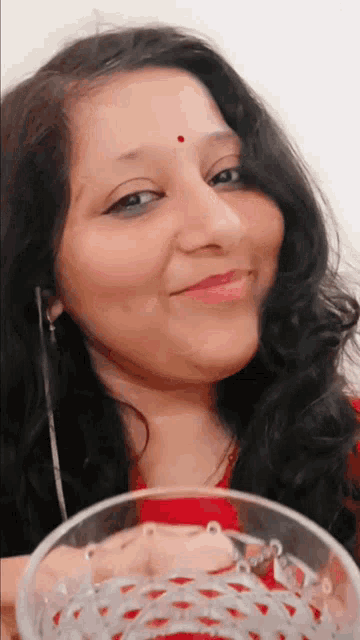 a woman with a red dot on her forehead is smiling