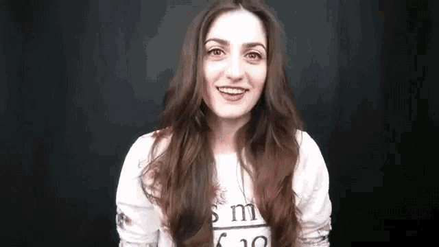 a woman with long hair is making a funny face and smiling .