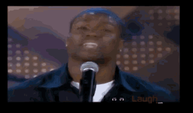 a man stands in front of a microphone with laugh.com written on the bottom of the screen