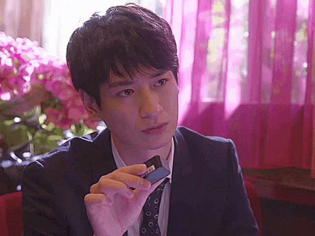 a man in a suit and tie is holding a piece of paper that says ' t.t. ' on it