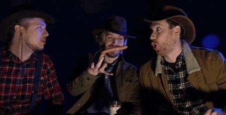 two men in cowboy hats are holding a hot dog