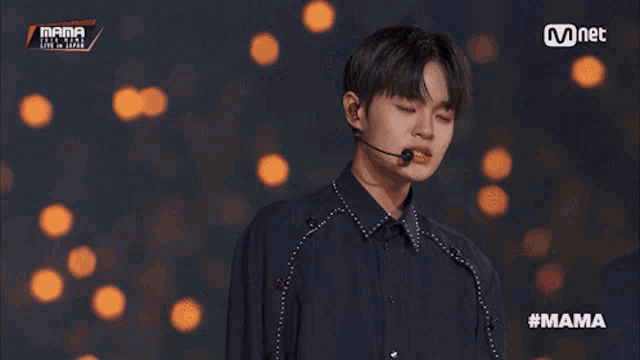 a man stands in front of a microphone at mama