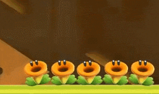 a row of cartoon plants with faces on them are standing next to each other on a green field .