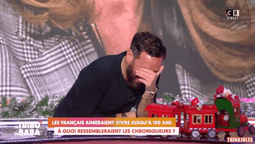 a man covering his face with his hand on a tv screen