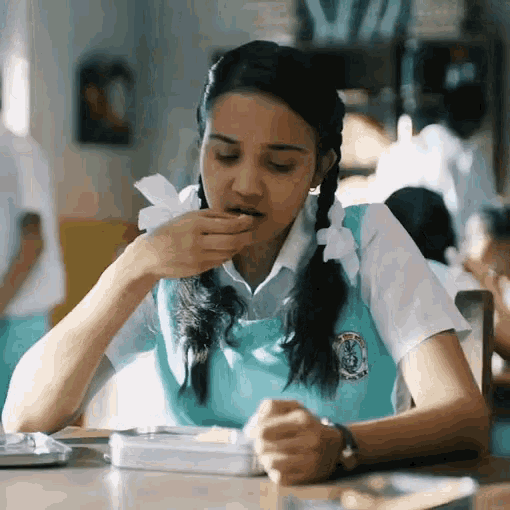 a girl in a school uniform is sitting at a table