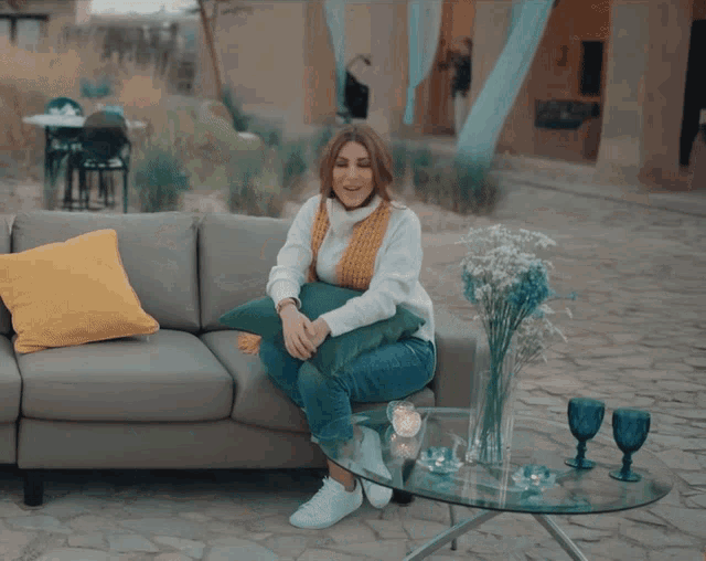 a woman sitting on a couch with her arms in the air