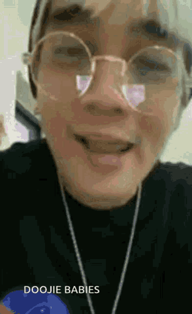 a close up of a person wearing glasses and a necklace