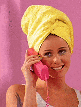 a woman with a towel wrapped around her head is talking on a pink phone