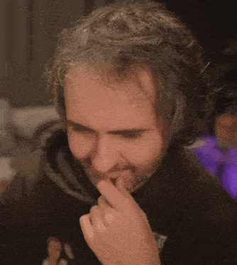 a man covering his mouth with his hand while wearing a black hoodie