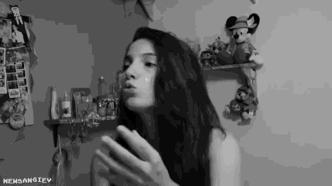 a girl blowing a kiss in front of a shelf with mickey mouse stuffed animals on it