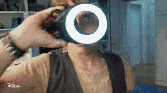 a man is taking a picture of himself with a camera with a ring light on it .