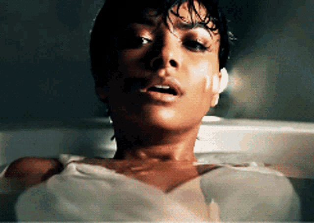 a woman is laying in a bathtub with a wet shirt on